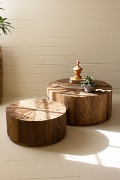 two wooden tables sitting next to each other on top of a white floor covered in plants