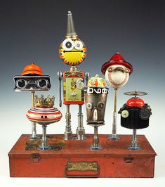 a group of different types of robot heads on top of a wooden box with metal fittings