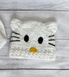 a crocheted hello kitty hat and mitten set on a white wooden surface