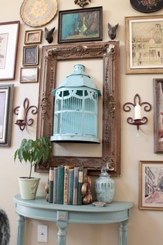 a birdcage is sitting on top of a table in front of many framed pictures