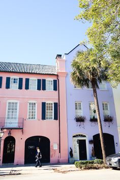 two pink buildings with black shutters and palm trees