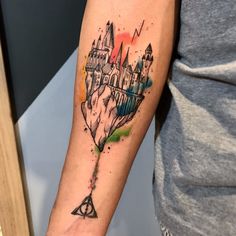 a harry potter tattoo with hogwarts castle on the back of his left arm