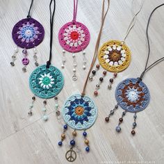 four crocheted medallions with beads hanging from them on a white wooden floor