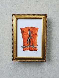 an orange pillow with a bird sitting on it in a gold frame hanging on the wall