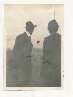 two people standing next to each other with a red heart in the middle of them