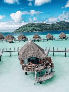 the water is crystal blue and clear with huts on stilts in the middle of it