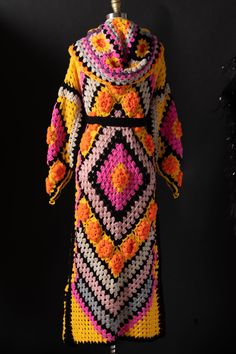 a crocheted coat is displayed on a mannequin's head stand