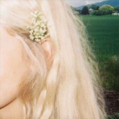 a woman with long blonde hair and a flower in her hair is staring into the distance