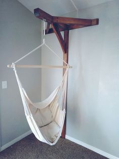 a white hammock hanging from a wooden beam in a room with carpeted flooring