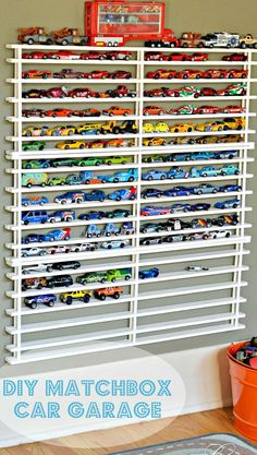 a white rack filled with lots of toy cars on top of a wall next to a window