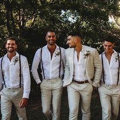 a group of men standing next to each other wearing white pants and pink vests