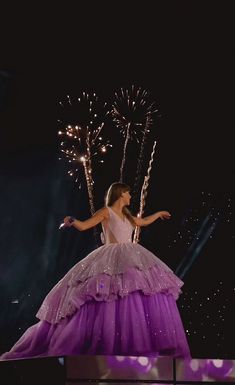 a woman in a dress on stage with fireworks