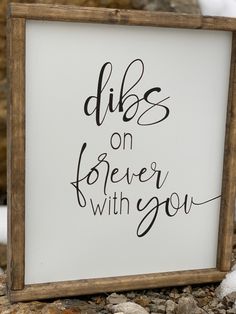 a sign that says dibs on forever with you next to some rocks and snow