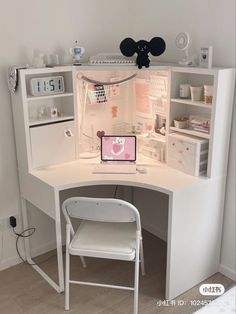 a white desk with a laptop on top of it next to a chair and shelf