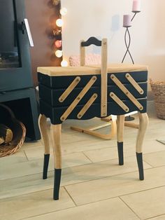 a black and white dresser with wooden handles on it's legs in front of a fireplace