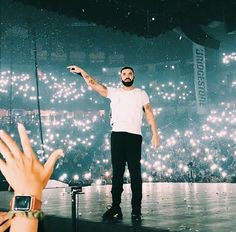 a man standing on top of a stage with his hand up in the air next to him