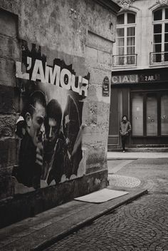 a black and white photo of a man standing in front of a wall with graffiti on it