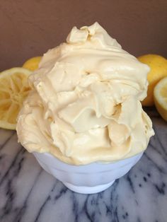 a white bowl filled with whipped cream next to lemons