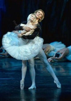 two ballerinas in white tutus and one is holding the other