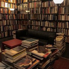 a room filled with lots of books and a black leather couch sitting in front of a book shelf