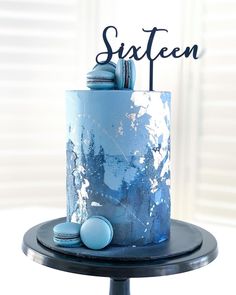 a blue cake with white frosting and some candies on the top that says sixteen