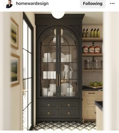 a kitchen with black and white checkered flooring next to a tall china cabinet