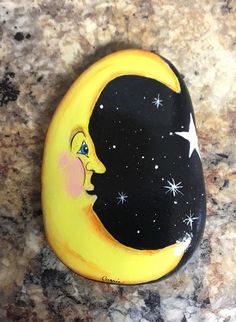 a painted rock with the moon and stars on it