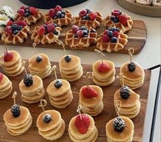 some waffles with berries and blueberries are on a wooden platter next to other desserts