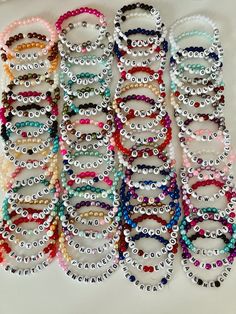 many different colored bracelets are lined up on a white surface with the words love spelled in