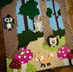 a crocheted blanket with animals and mushrooms on it