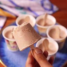 a hand holding an ice cream on top of a blue plate