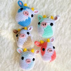 four crocheted animal keychains on a white carpet with one cow and the other pig