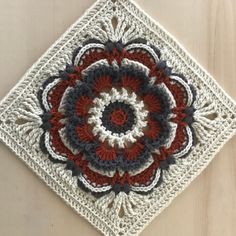 a crocheted square with a red, white and blue flower in the center