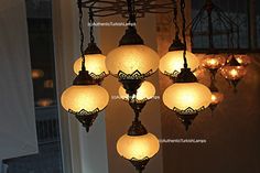 a chandelier with six lights hanging from it's sides in front of a window