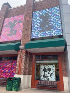 the front of a store with mickey mouse paintings on it's windows and benches