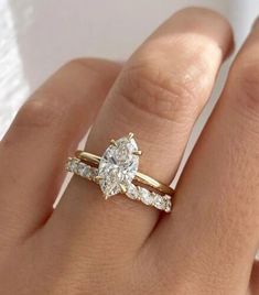 a woman's hand with two engagement rings on top of her finger and the other half