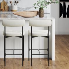 two white stools sitting on top of a wooden floor next to a kitchen counter