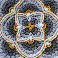the crocheted flower is made up of yellow and gray yarn, with white petals