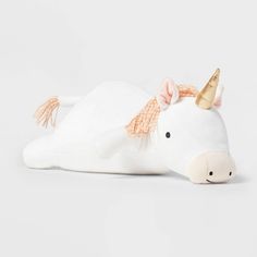 a white stuffed animal laying down with a gold horn on its head