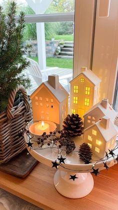 christmas decorations on a tray with pine cones and candles in front of a window sill