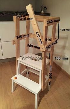 a wooden step stool sitting on top of a hard wood floor next to a kitchen