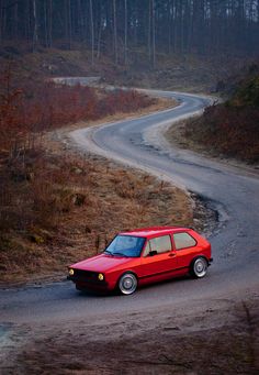 a red car driving down a winding road