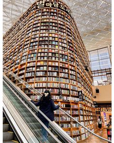 a person riding an escalator in front of a large book shelf filled with books