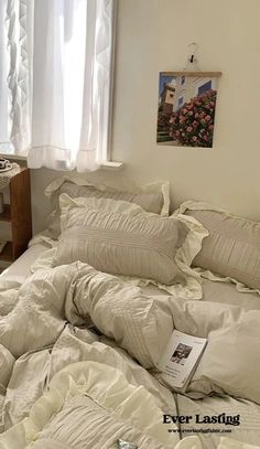 an unmade bed with white sheets and pillows in a bedroom next to a window