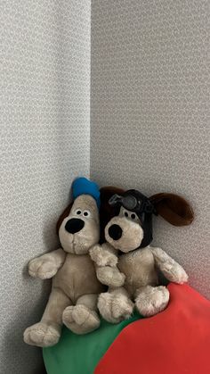 two stuffed dogs sitting on top of each other in front of a wallpapered background