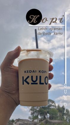 a person holding up a cup with a straw in it and the words kulo written on it