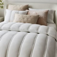 a bed with white comforter and pillows on it
