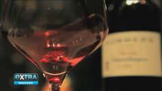 a close up of a wine glass with red wine in it and a bottle behind it