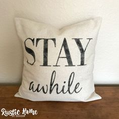 a pillow that says stay awhile on the front, and black lettering on the back