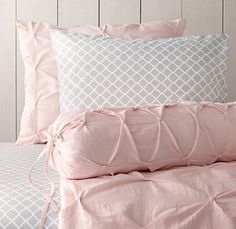 a bed with pink sheets and pillows on it